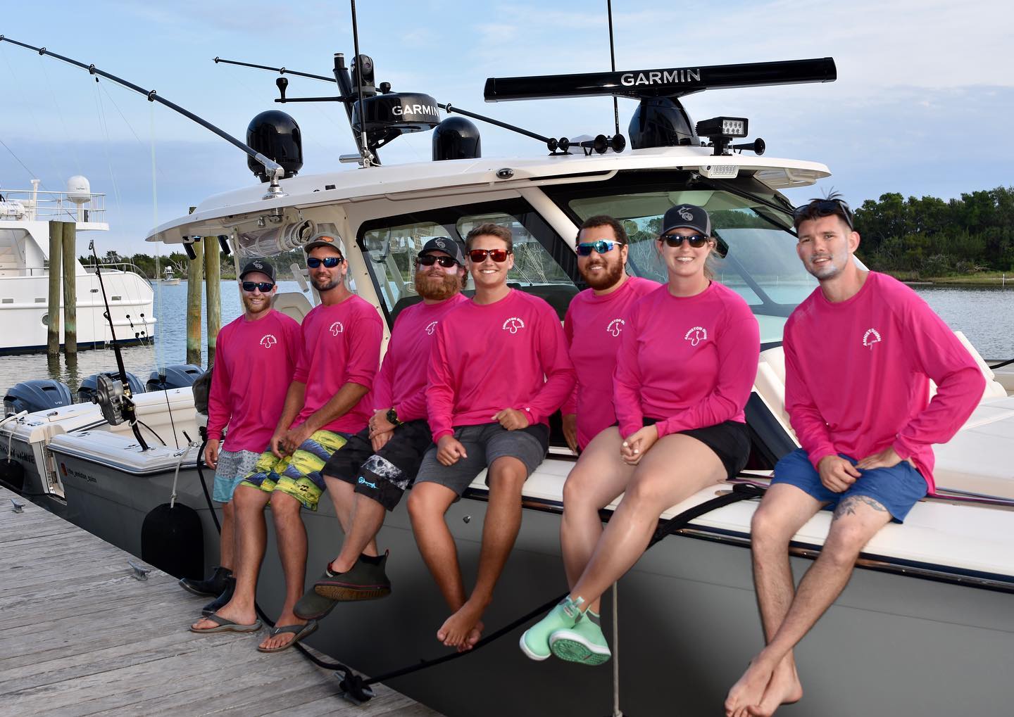Grady-White boat with a group of people in matching pink shirts docked at a marina.