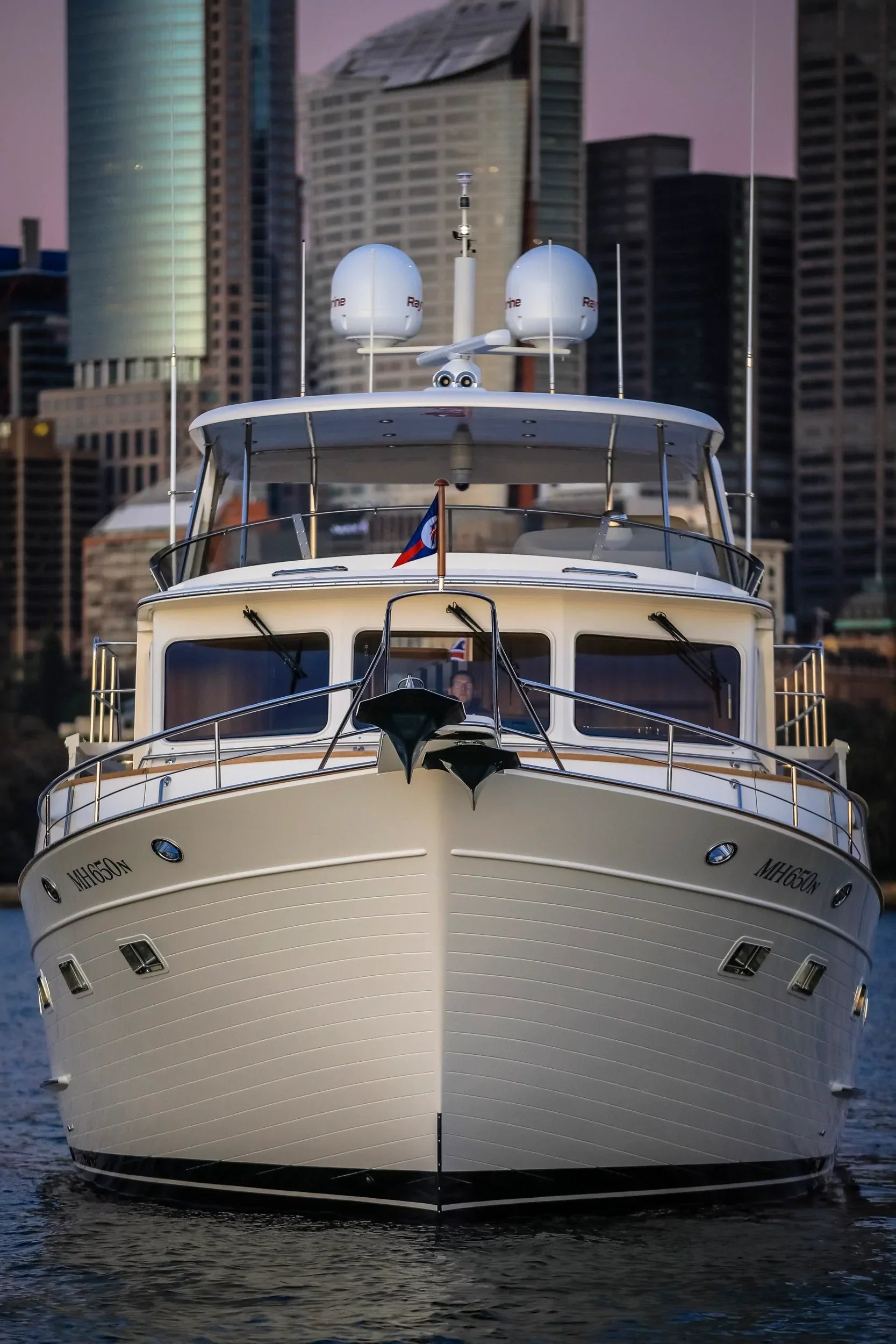Model #72 custom mast installed on Fleming 65 yacht with city skyline in background.