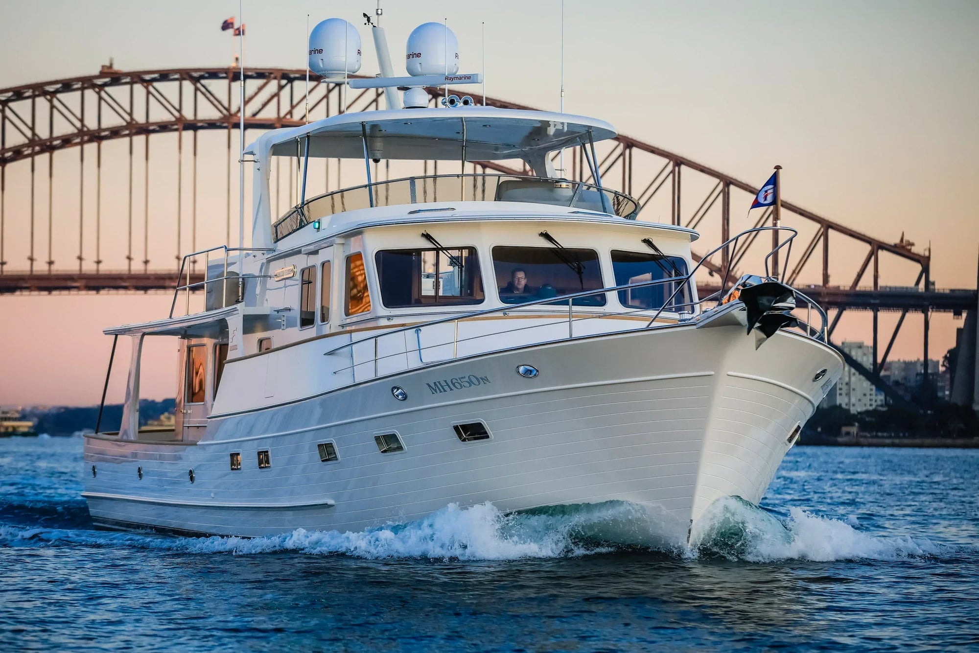 Fleming 65 yacht with Model #72 custom mast installed, cruising near a bridge.
