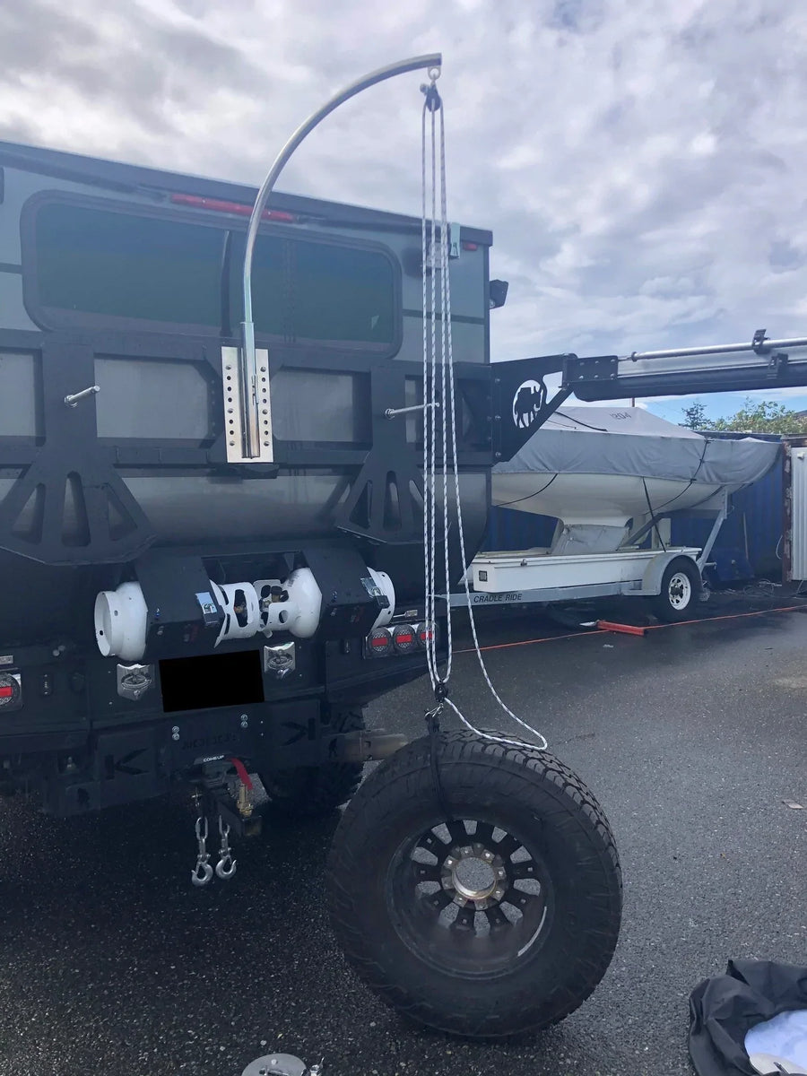 Spare tire lifting davit mounted on an overland vehicle for changing flat tires.
