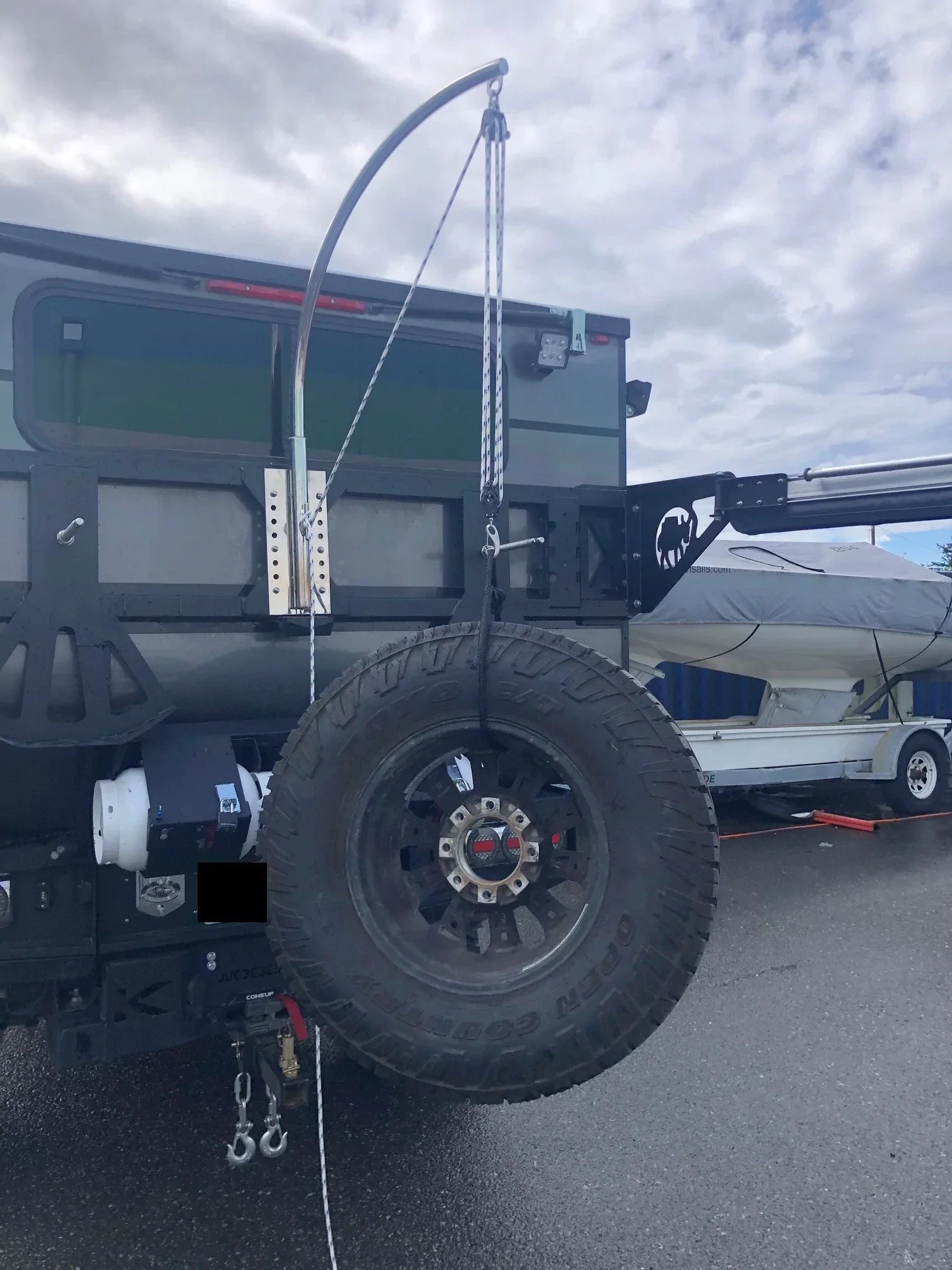 Spare tire lifting davit attached to an overland vehicle for flat tire changing.